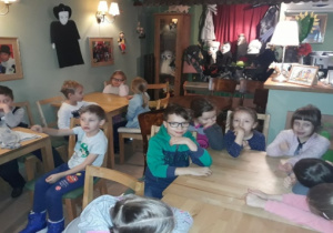 Dzieci siedzą przy stolikach, ogladają przedstawienie.
